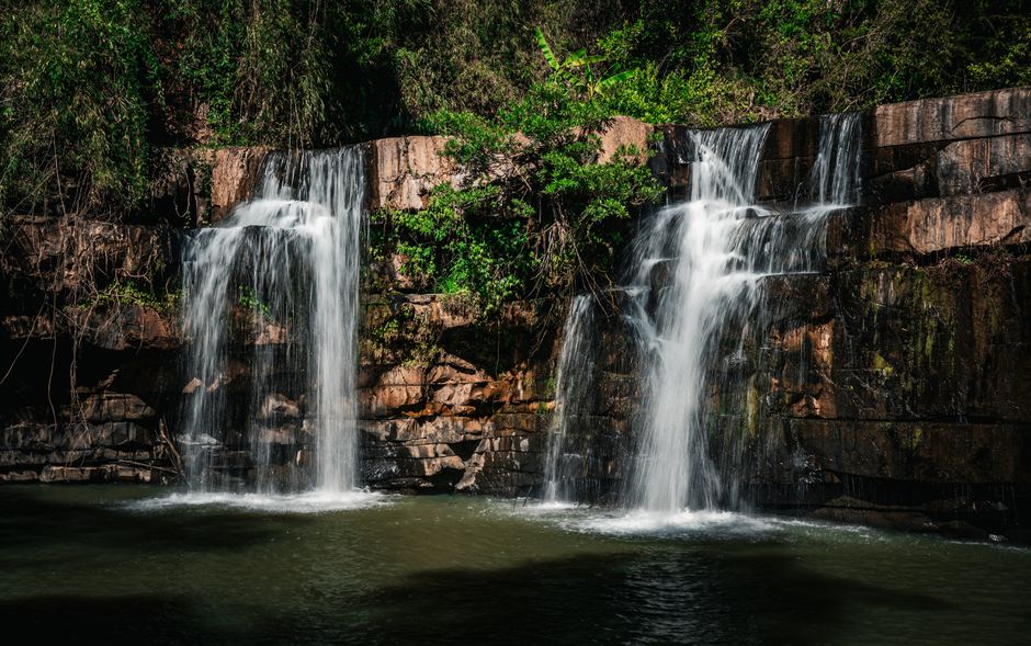 A serene waterfall cascading over rocks in the lush forest of Thailand.