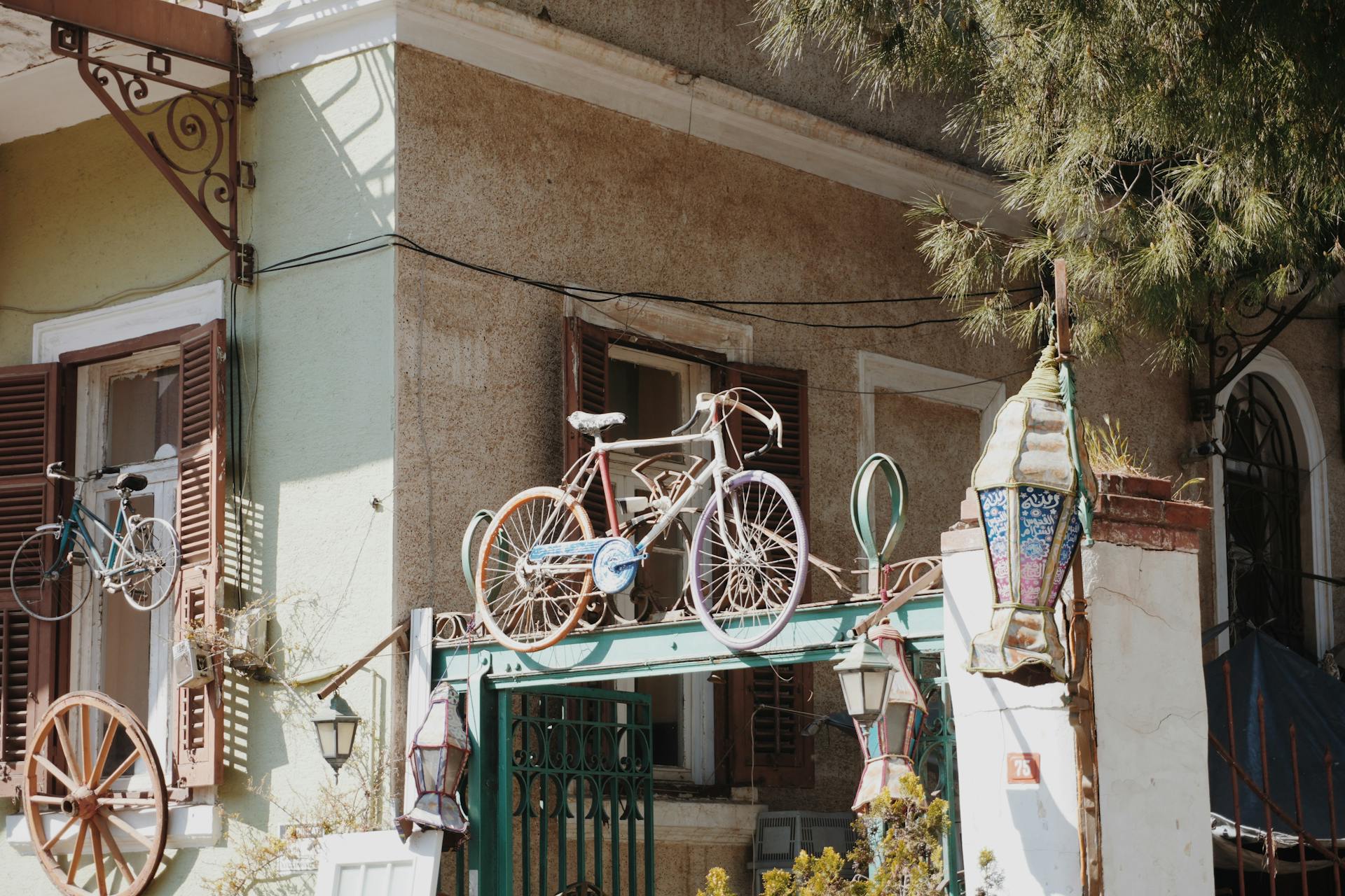 A vintage house facade adorned with hanging bicycles and ornate lanterns in a sunny setting.