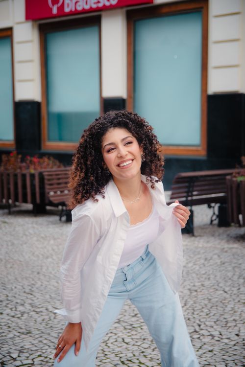 Free Joyful woman in casual attire posing outside on a cobblestone street. Stock Photo