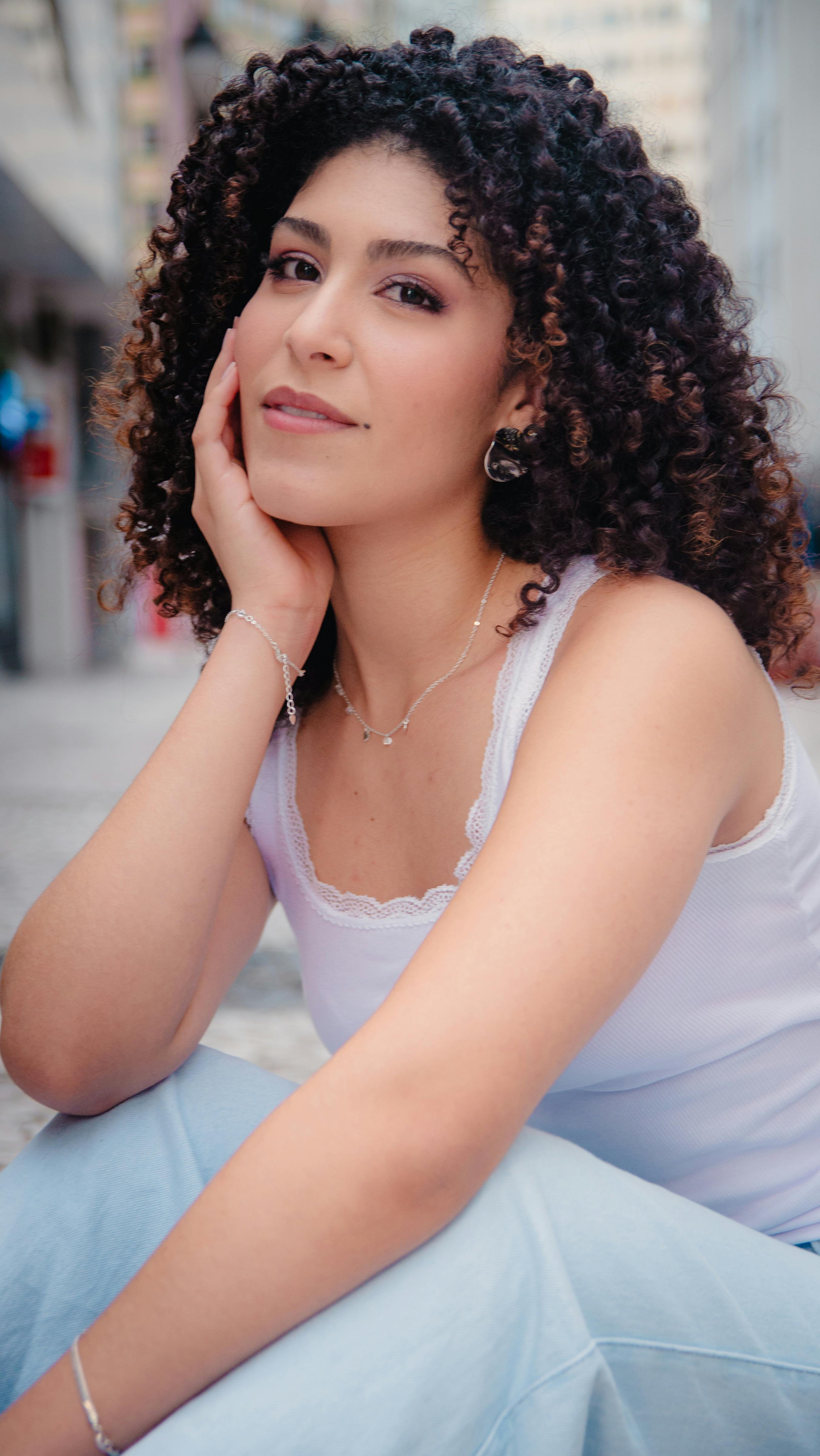 Portrait of a confident woman with curly hair in a lively urban environment.