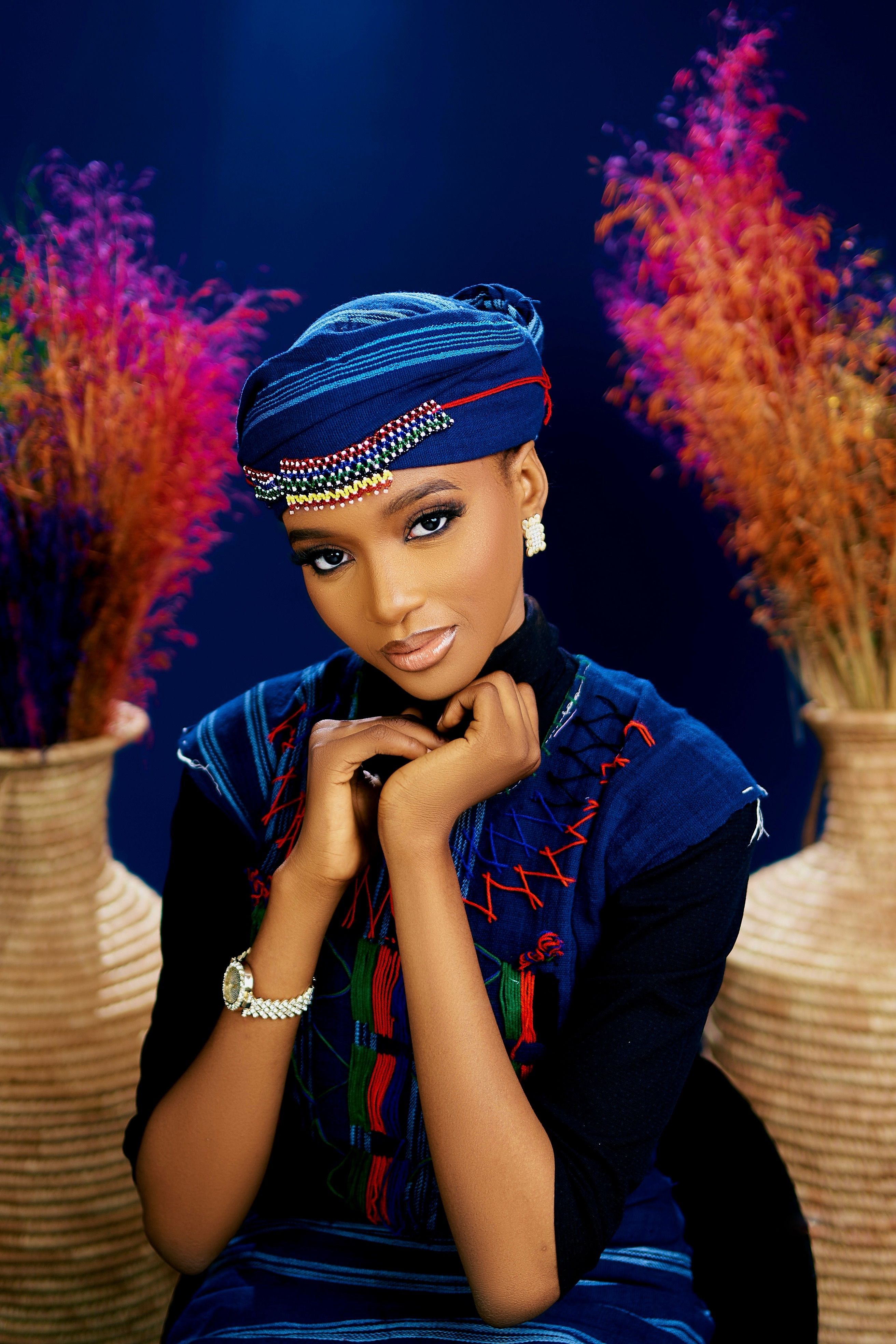 Portrait of a woman in traditional blue attire, vibrant floral backdrop enhancing elegance.
