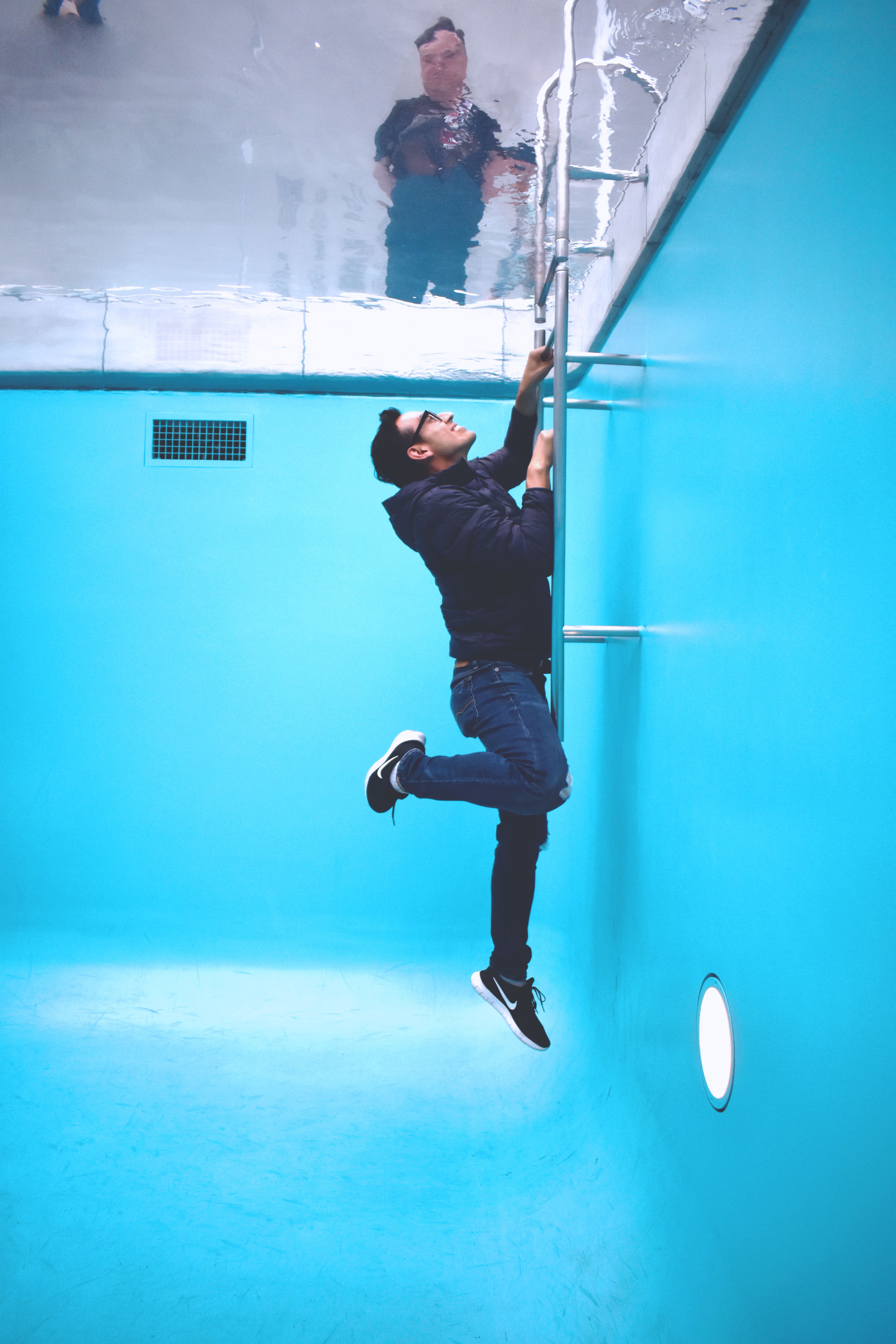 Creative optical illusion of a man climbing a ladder inside a swimming pool art installation in Kanazawa, Japan.