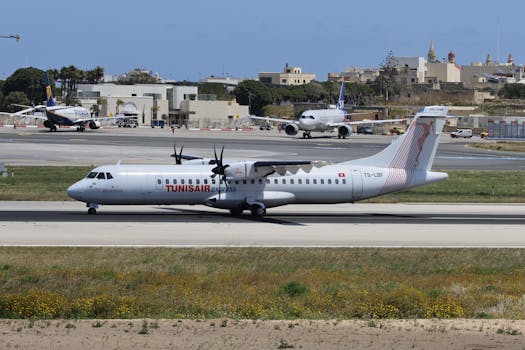 Tunisair Express plane on the runway at Malta International Airport during daytime.