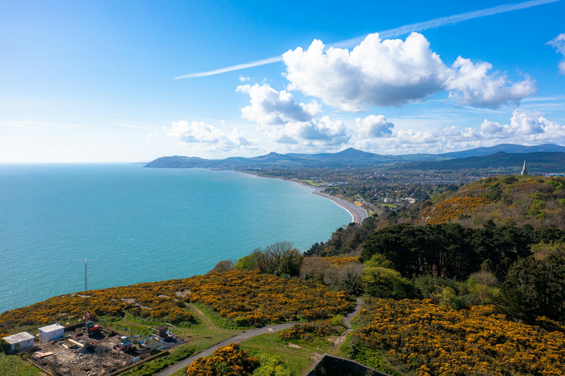 Aerial shot of Dublin Bay coastline from Howth Summit, Ireland, under a clear blue sky.