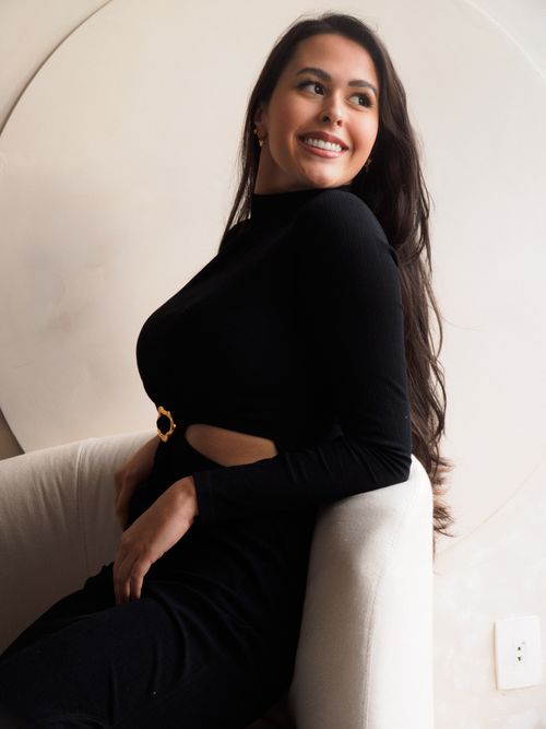 Free Elegant woman in a black dress seated indoors, smiling and looking away from the camera. Stock Photo