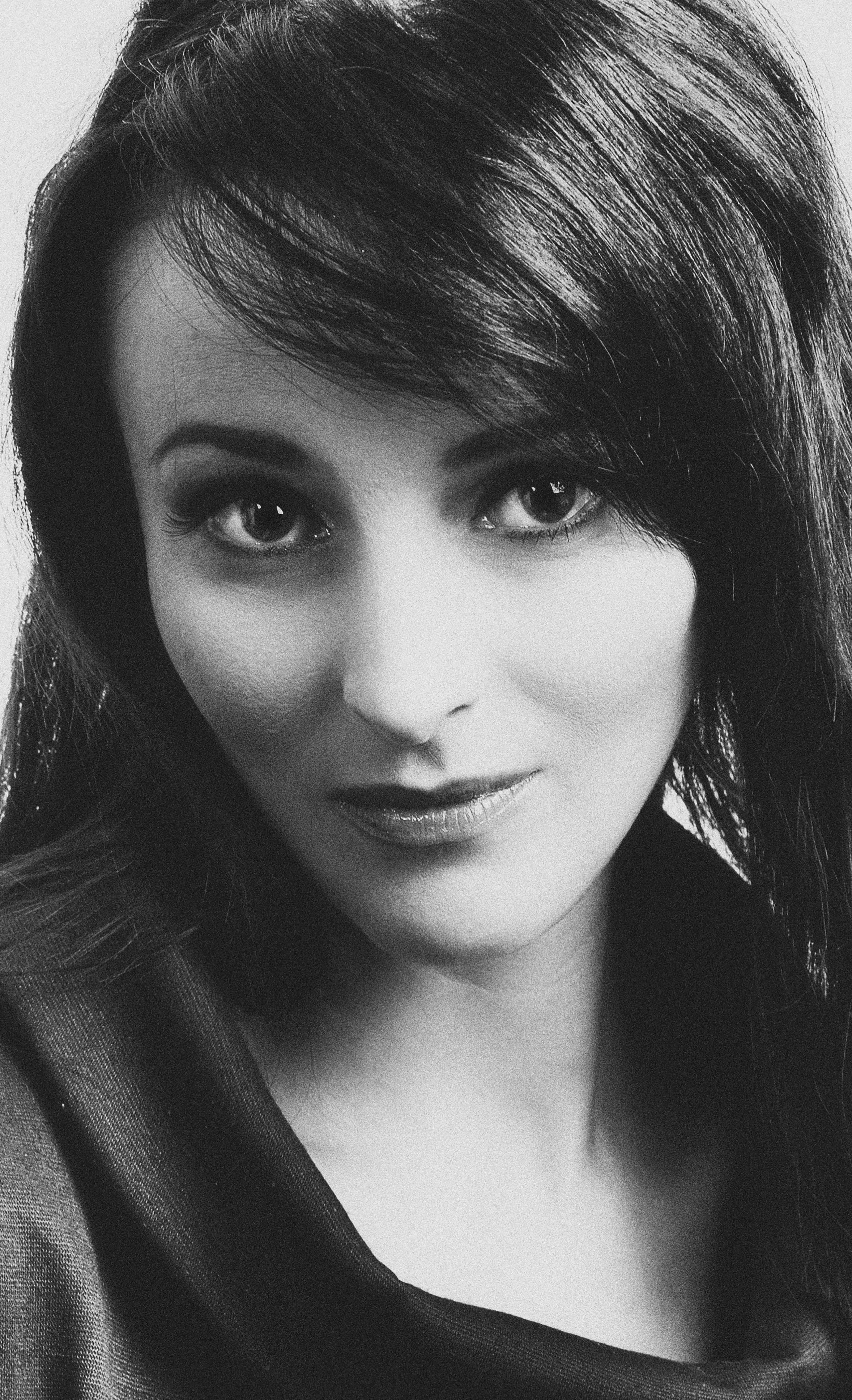 Captivating black and white portrait of a young woman with an enigmatic expression.