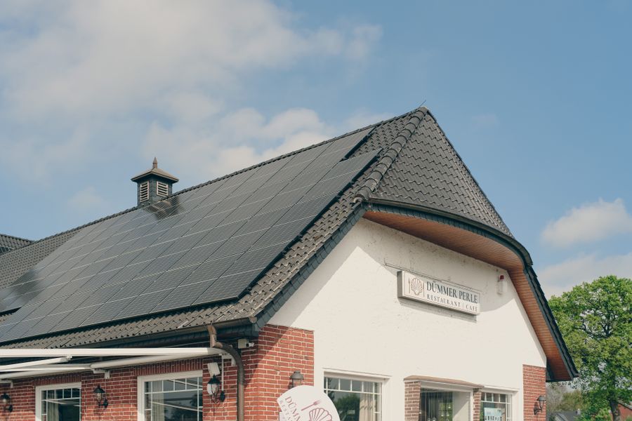 A red brick building with solar panels on the roof, under a clear blue sky, symbolizing sustainability and renewable energy.