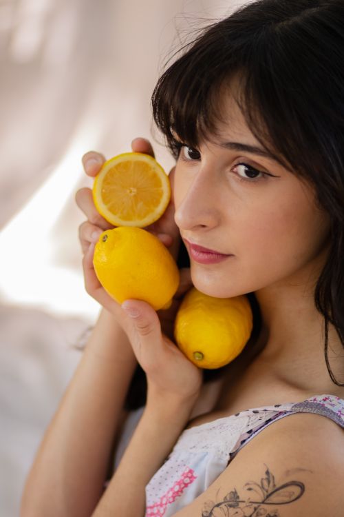 Free Young woman holding lemons in gentle light, portrait style. Stock Photo