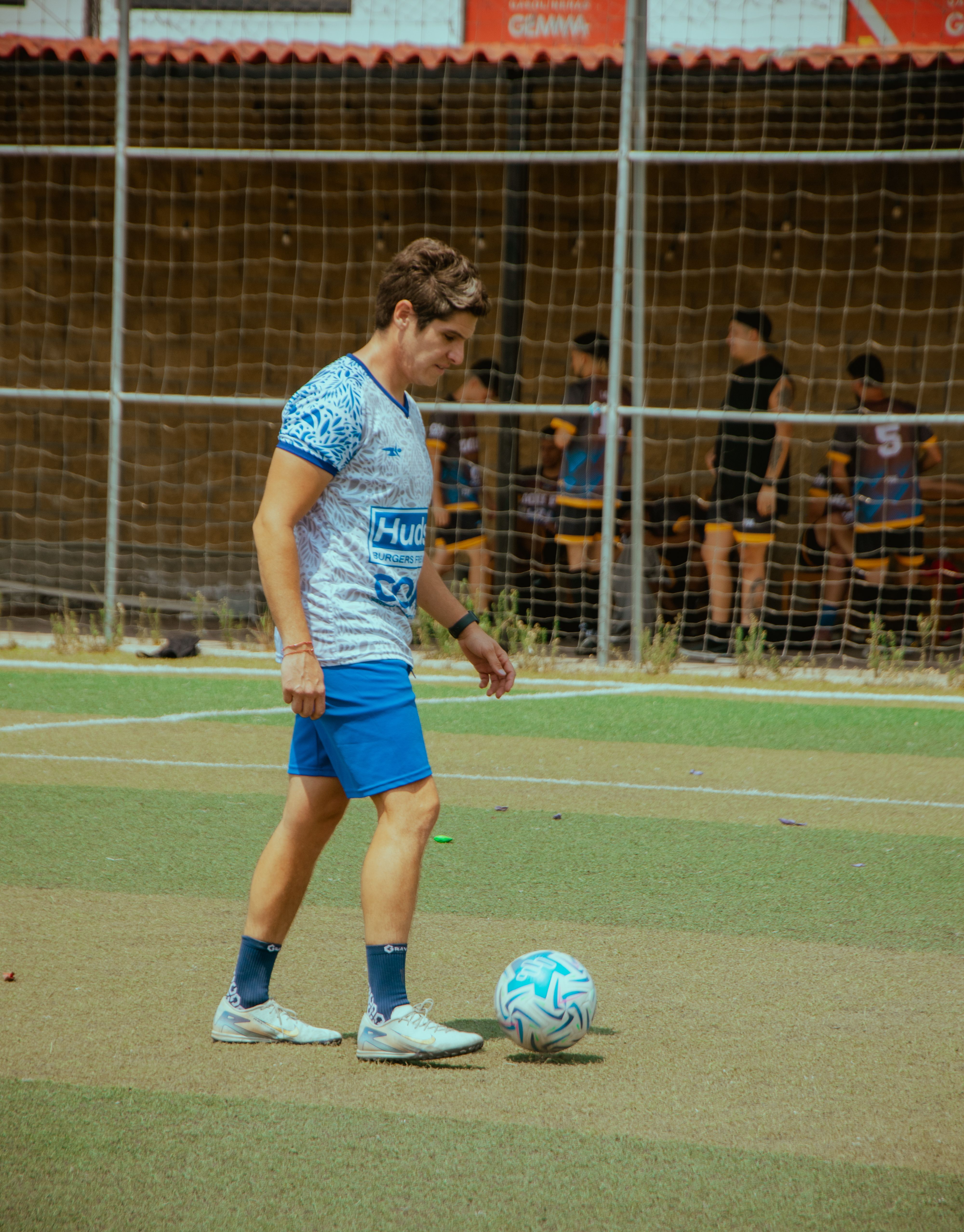 Young soccer player focuses on training with ball on turf field in bright daylight.
