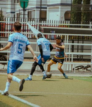 Dynamic scene of local players competing fiercely in a small football match outdoors.