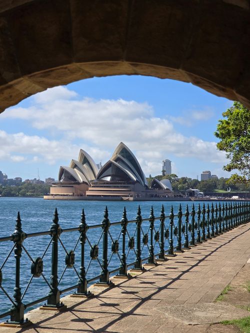Free Dramatic angle of Sydney Opera House framed by archway with bright blue sky. Stock Photo
