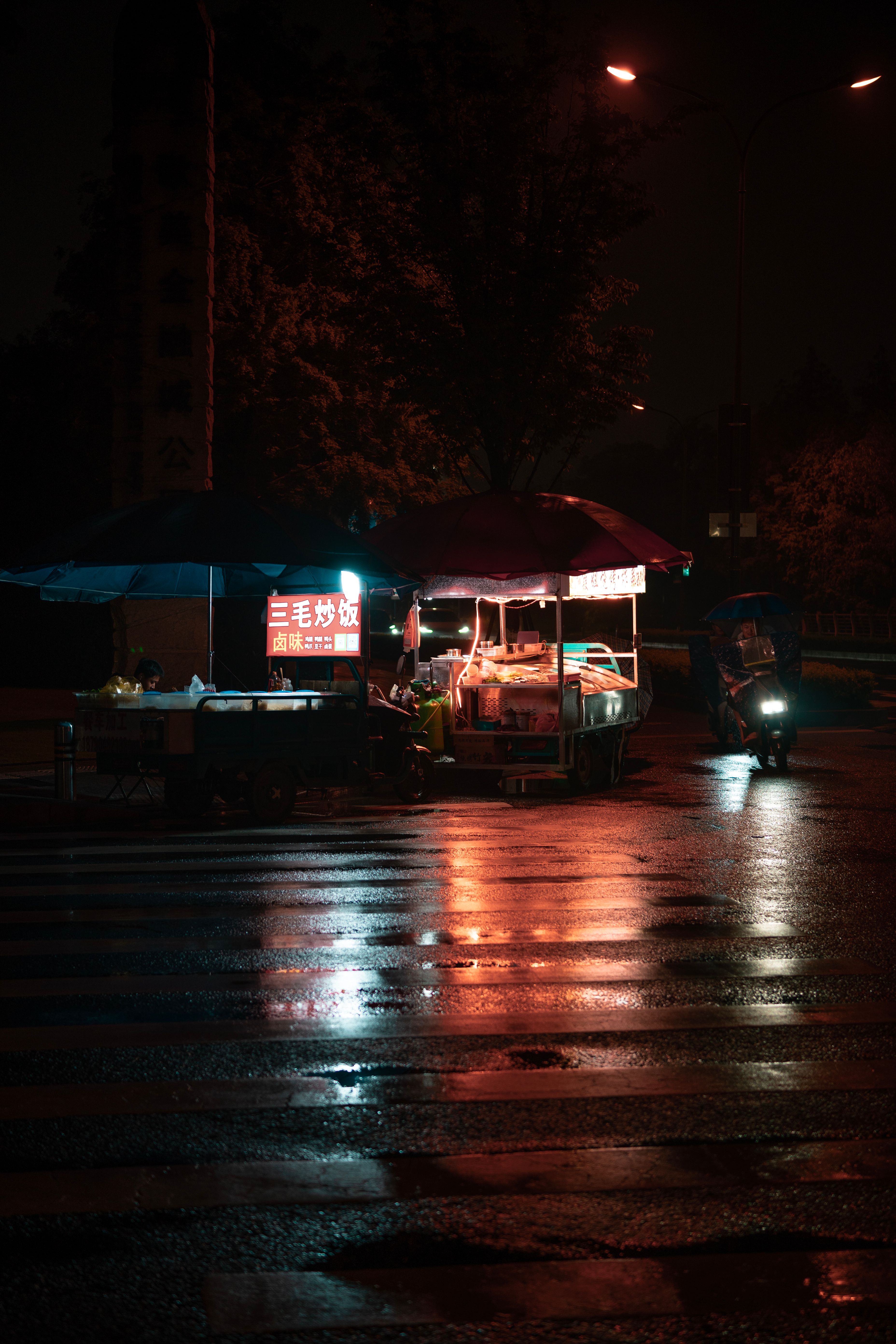 A vibrant night scene of a street food stall illuminated by neon lights.