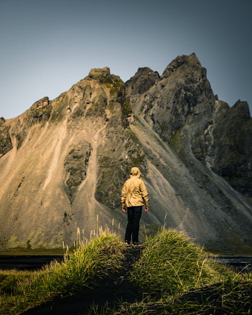 Person Standing on Grass Near Mountain