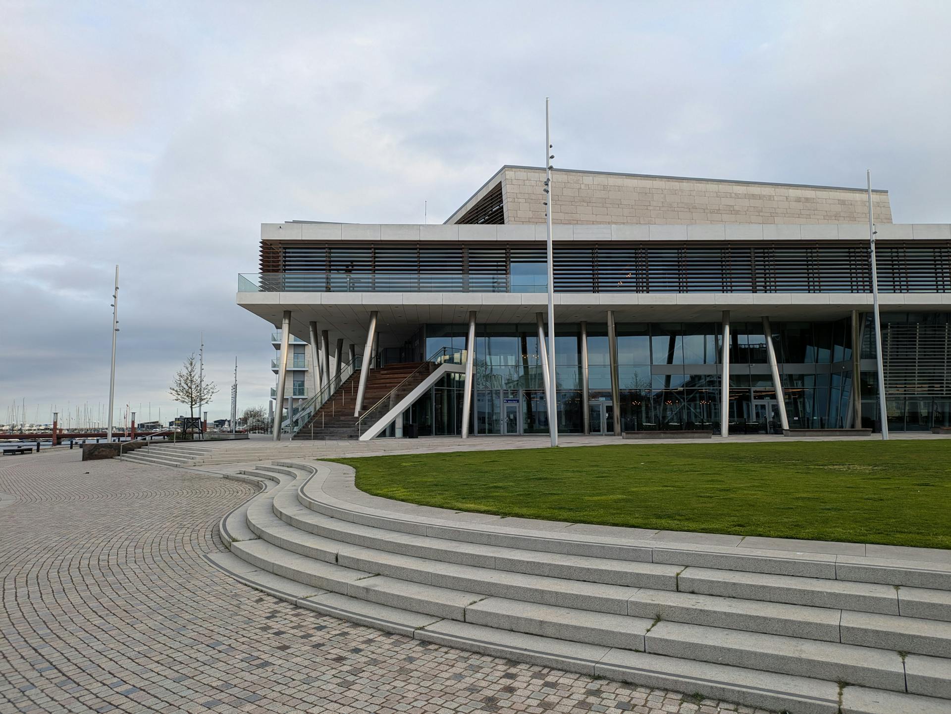 Contemporary architecture of a building near the waterfront with steps and landscaped green area.