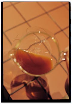 Warm-toned artistic photo of coffee in a glass decanter on a tiled surface.