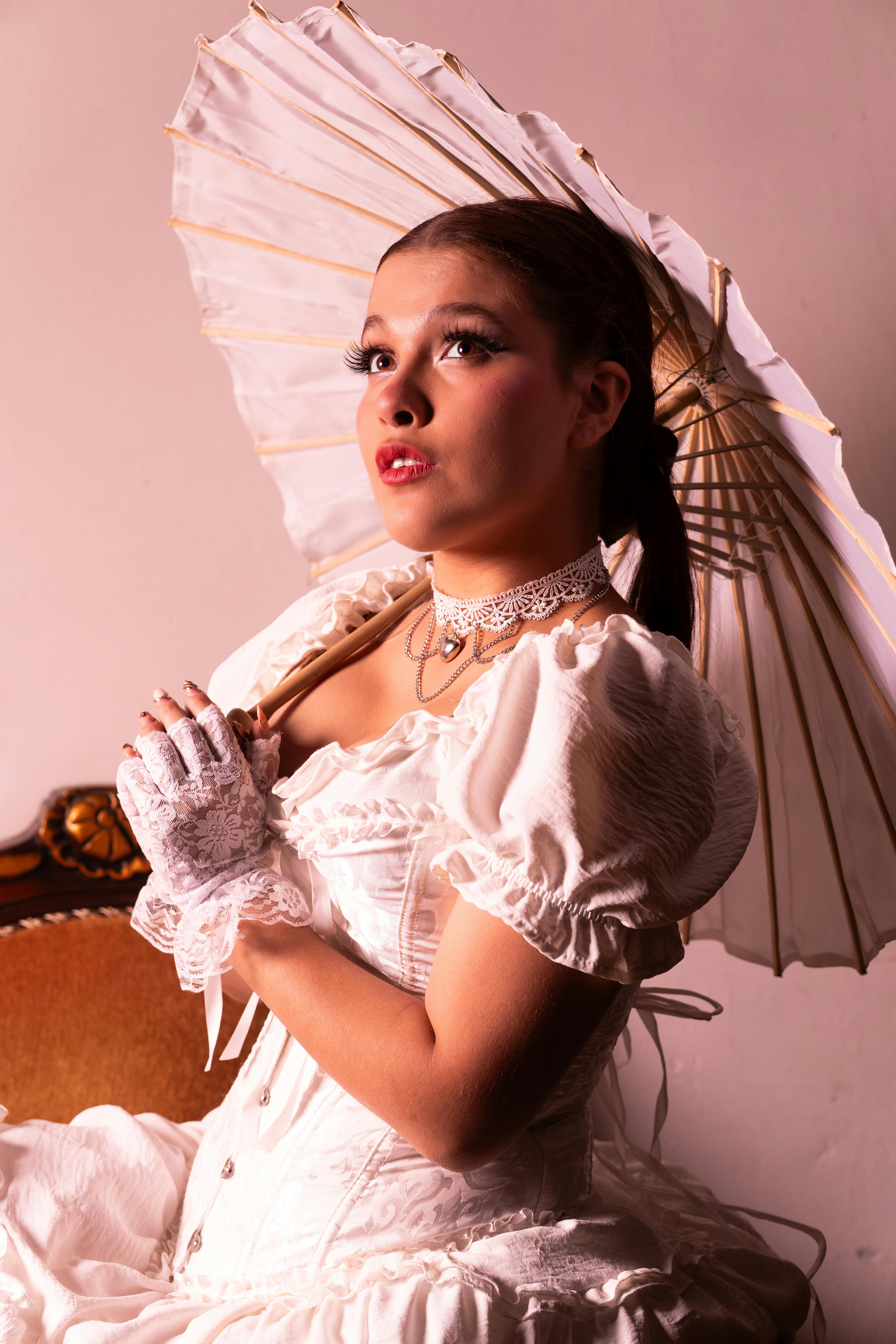 bezplatná Okouzlující portrét ženy ve vintage oblečení držící slunečník, vyzařující eleganci a styl. Základová fotografie