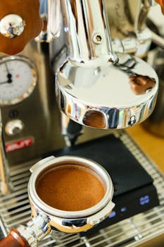 Detailed close-up of an espresso machine portafilter preparing coffee.