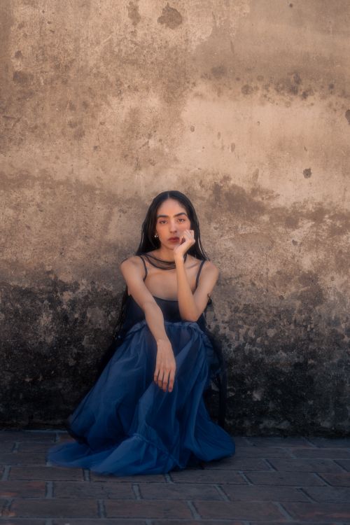 Elegant Woman in Blue Dress Against Rustic Wall · Free Stock Photo