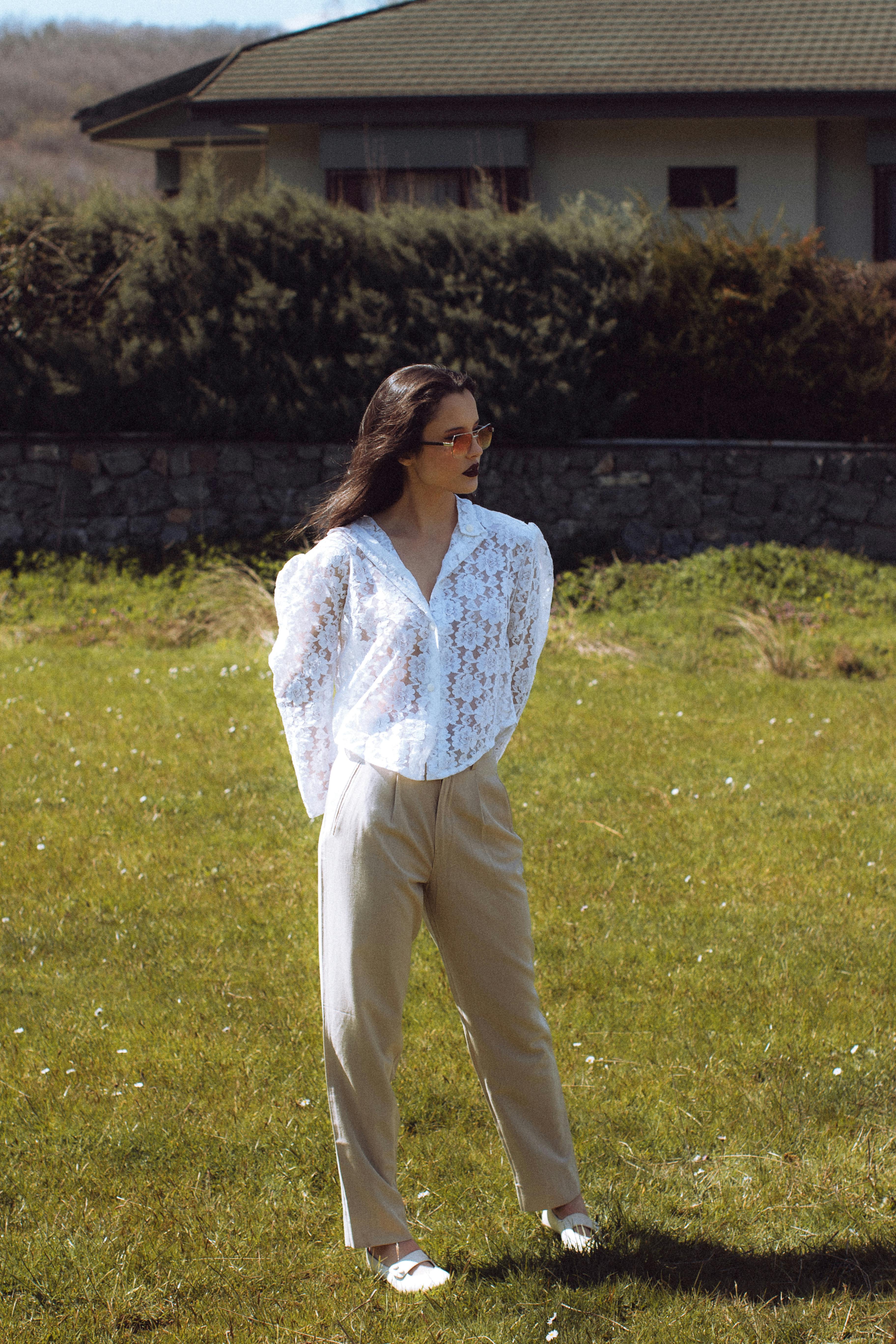 Fashionable woman in white lace top standing outdoors in İstanbul, Türkiye.