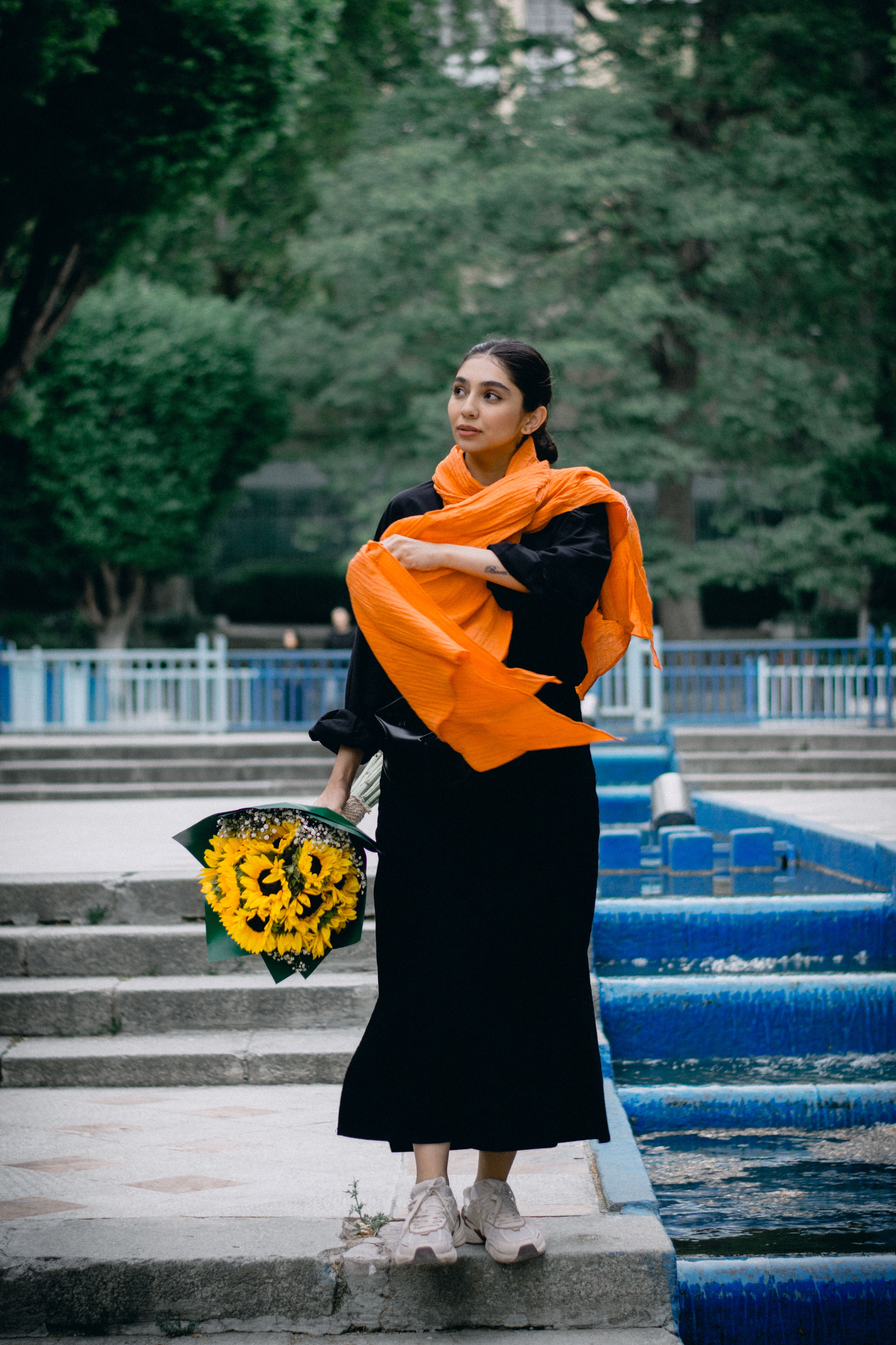 Woman with Sunflowers in Urban Park Setting · Free Stock Photo