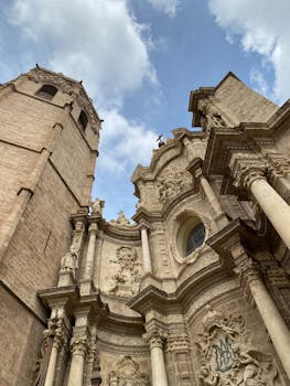 A stunning upward view of the Baroque facade of Valencia Cathedral under a blue sky.