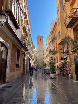 Charming street in Valencia featuring a historic tower under a clear blue sky.