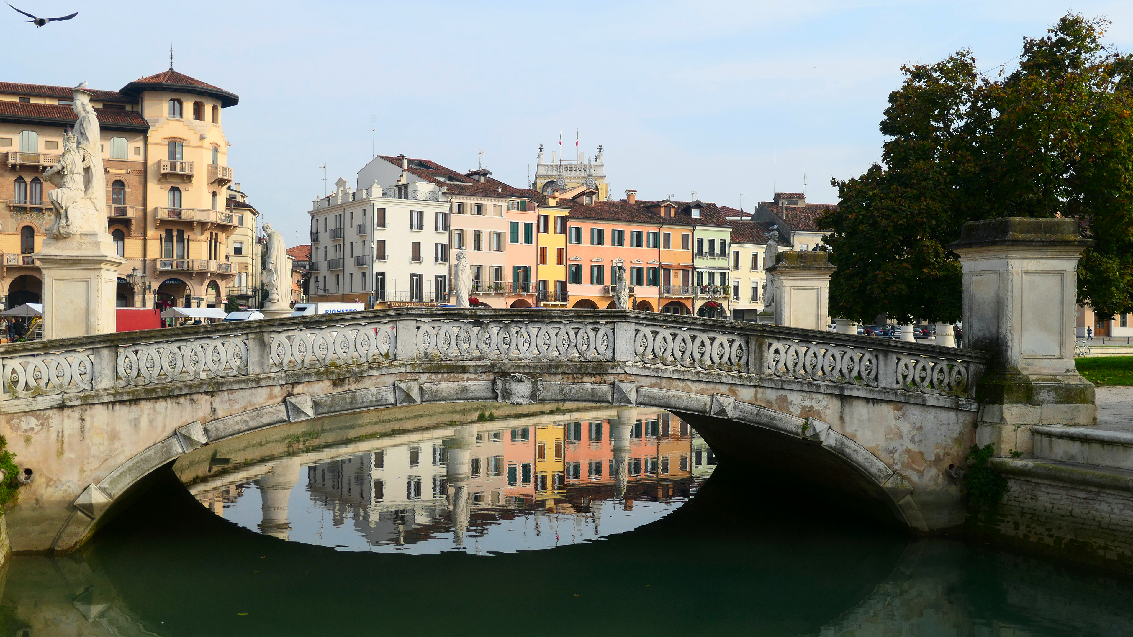 Scenic view of Prato della Valle with a historic bridge and colorful Venetian buildings in Padova, Italy.