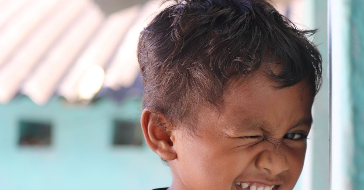 Kid Winking Smiling Child Winking in Vibrant Outdoor Setting · Free Stock Photo