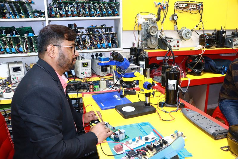 Technician working on air conditioning electronics in a lab setting