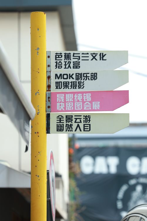 Free Outdoor directional sign with Chinese text pointing to cultural and commercial destinations. Stock Photo