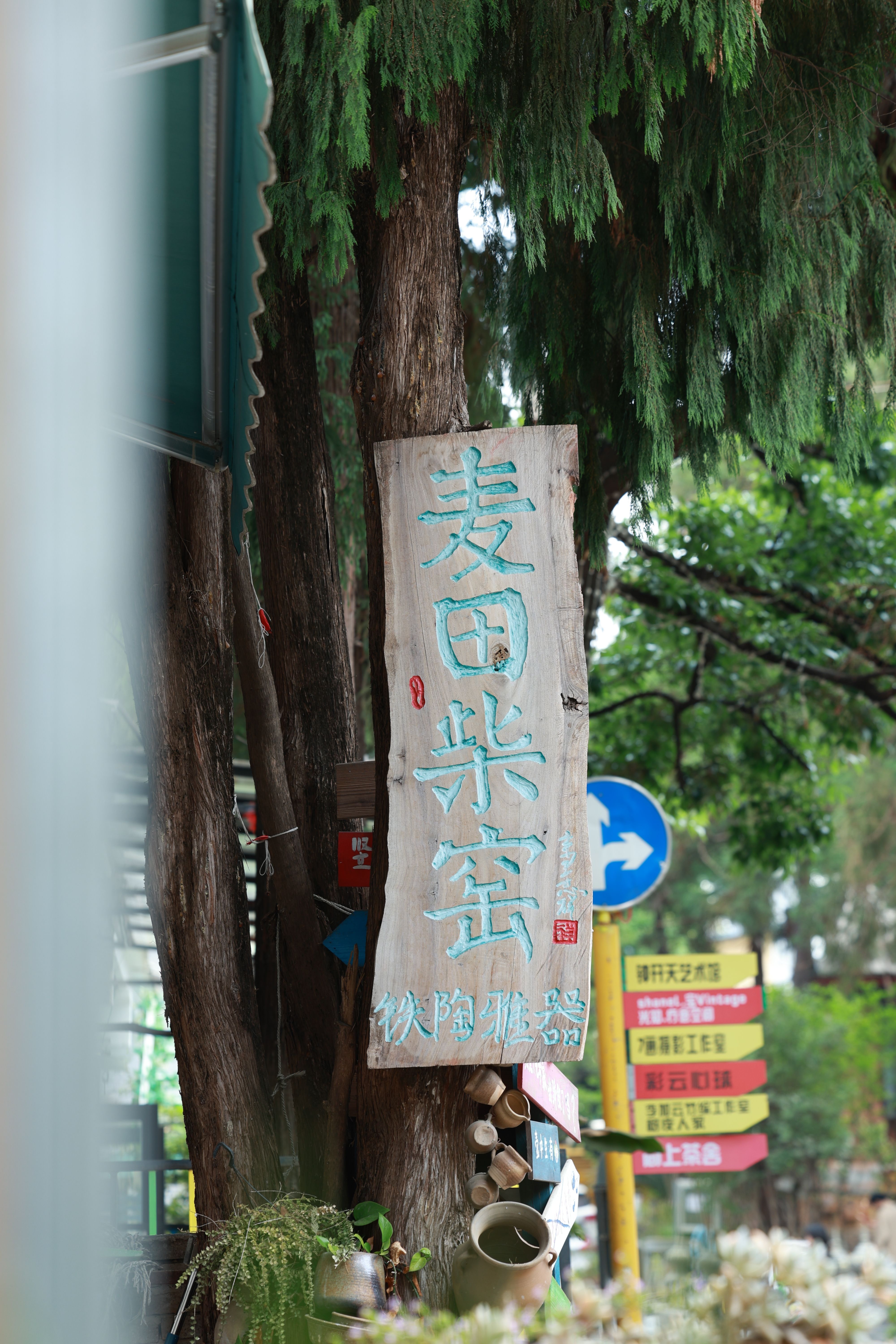 Wooden sign with Chinese characters against a lush urban backdrop.