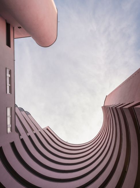 Abstract view of a curved building facade looking upwards to the blue sky.