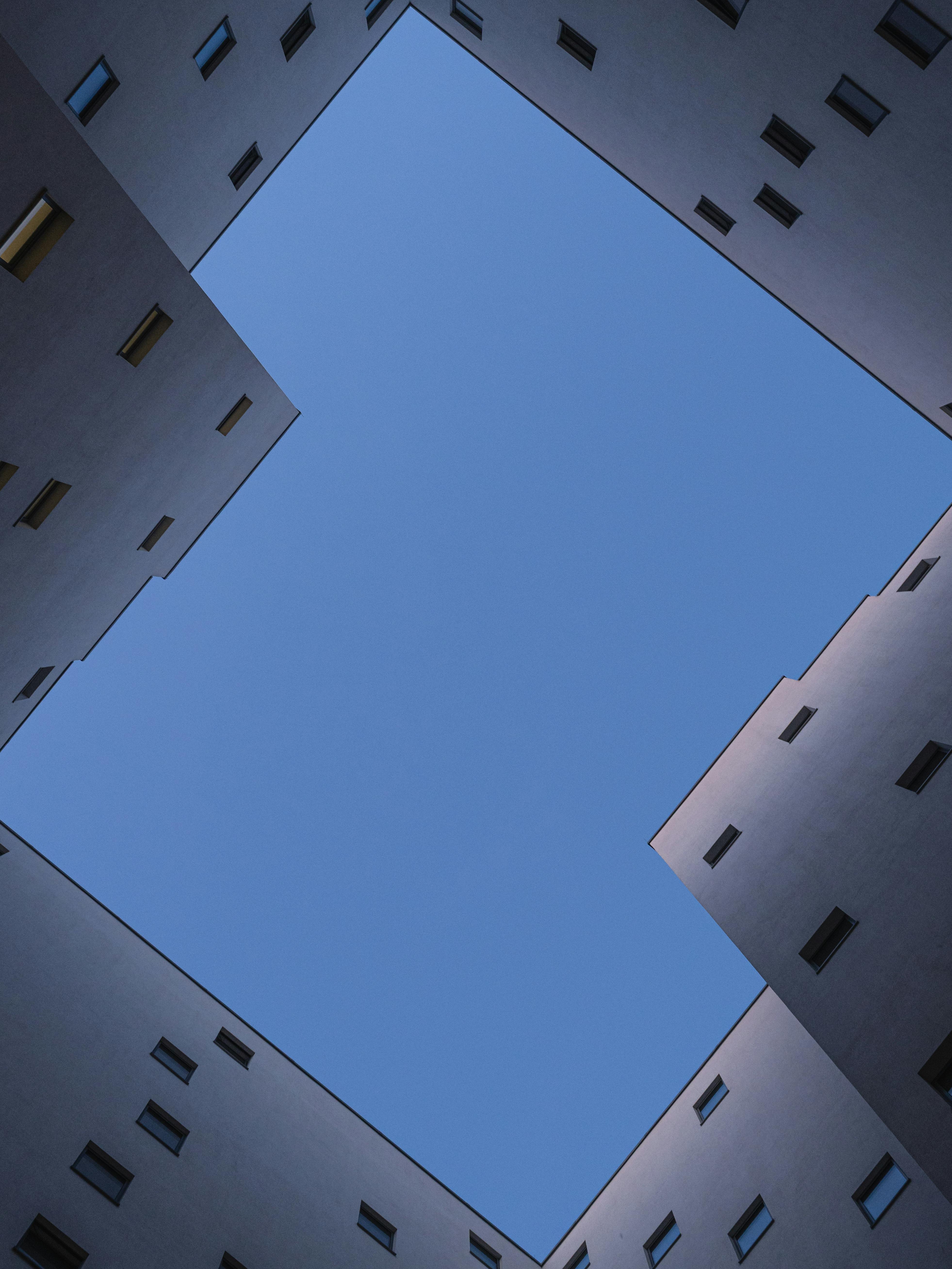 View upwards of symmetrical building architecture framing a clear blue sky.