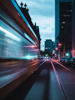 Blurred motion of a tram speeding through a city street at night, capturing dynamic urban life.