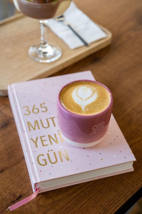 Free Cup of latte with heart art on pink journal in a café, perfect morning setup. Stock Photo
