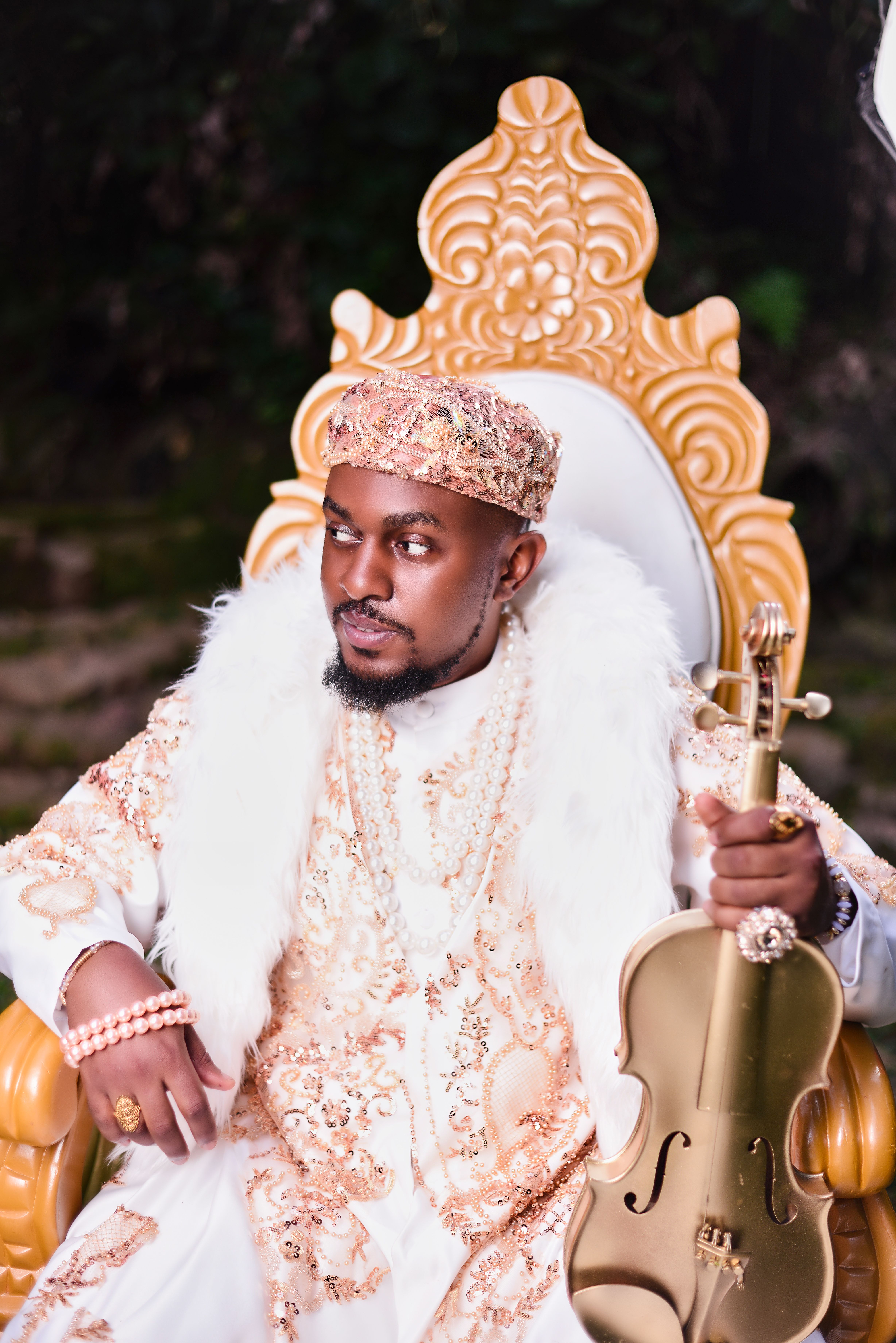 Elegant portrait of a musician wearing traditional royal attire and holding a violin, in Kampala, Uganda.