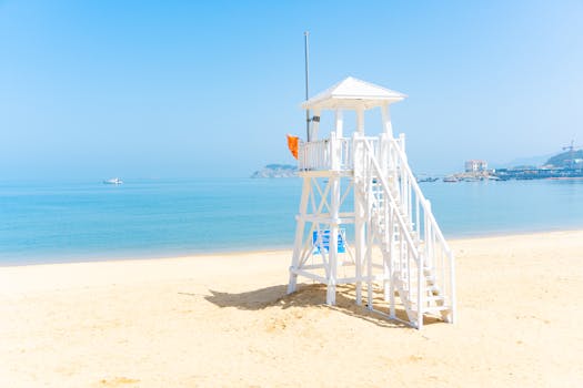 A tranquil beach scene featuring a white lifeguard tower, clear water, and blue sky.