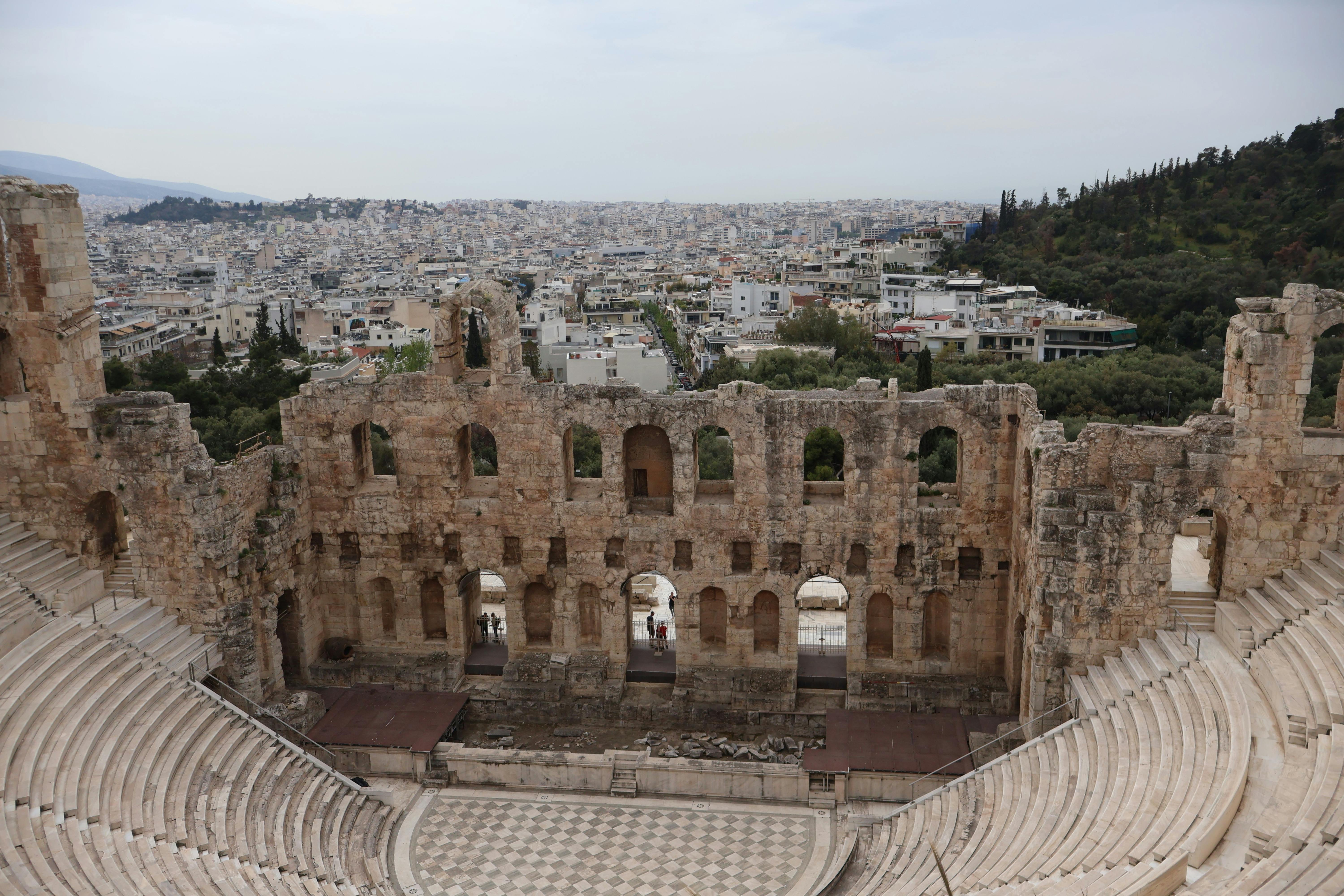 grátis Explore a grandiosidade de um antigo anfiteatro em Atenas, com vista para a paisagem urbana. Foto profissional