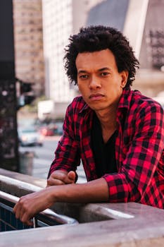 圣保罗街头，一名身穿格子衬衫、留着非洲式发型的男子正在沉思