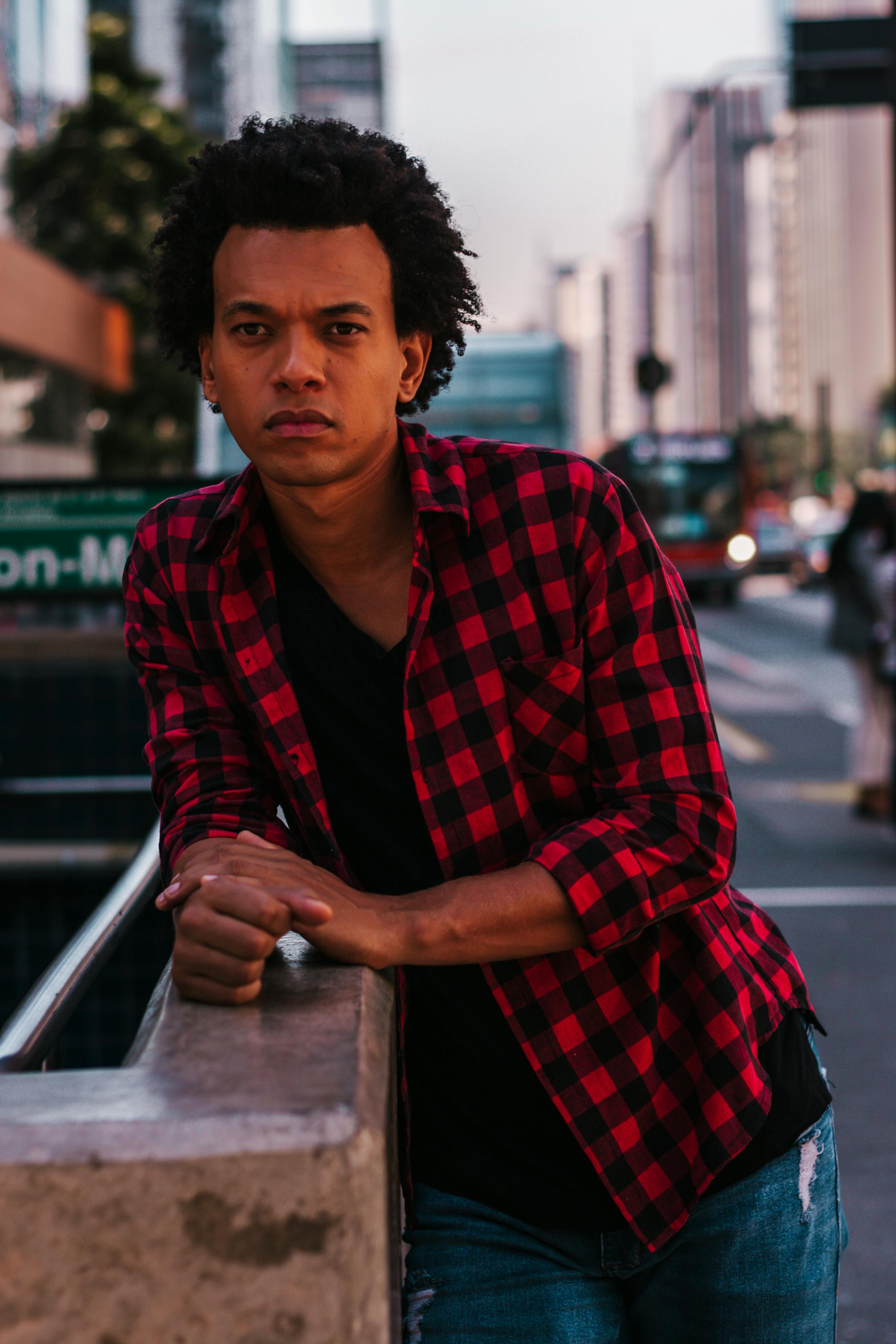 一名时尚男子身穿红色格子衬衫，在圣保罗繁华的街道上摆姿势