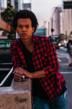 一名时尚男子身穿红色格子衬衫，在圣保罗繁华的街道上摆姿势