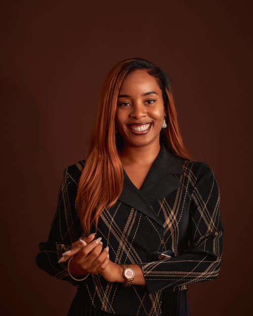 Free Portrait of a confident woman smiling in elegant attire against a brown background. Stock Photo