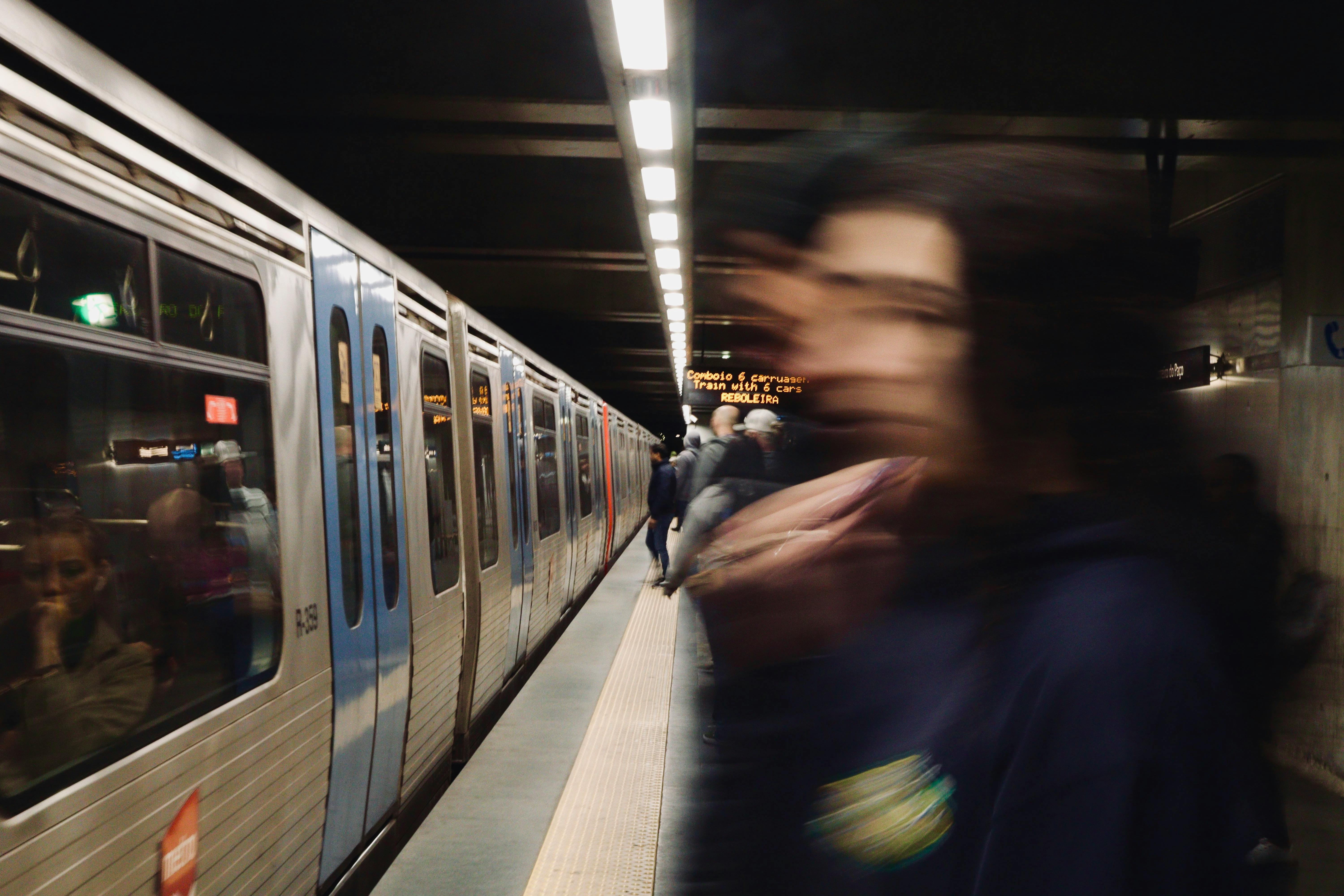 Blurred figure and subway train in a bustling underground station.
