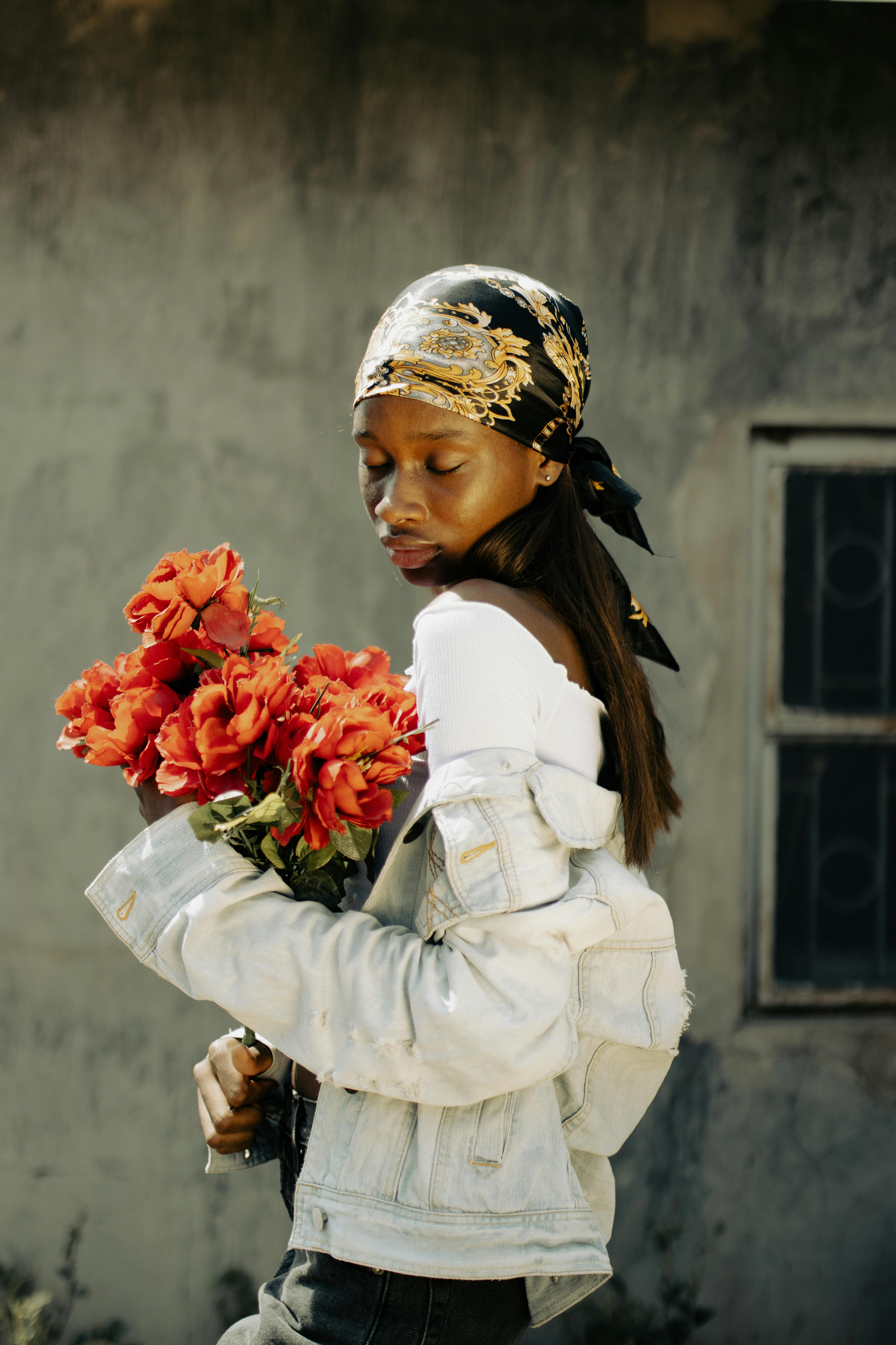 A young woman in Lagos, Nigeria, holding bright red flowers, embodying elegance and natural beauty.