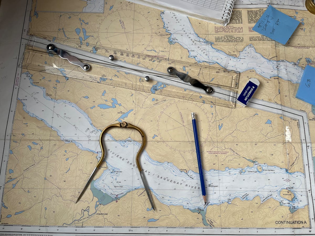 Carta nautica con compasso, righello parallelo e matita su tavolo