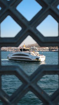 A ferry cruising on a sunlit day, beautifully framed by intricate iron architecture.