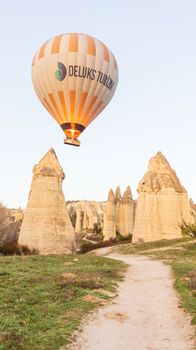 Hot air balloon soaring above Cappadocia's iconic fairy chimneys during sunrise.