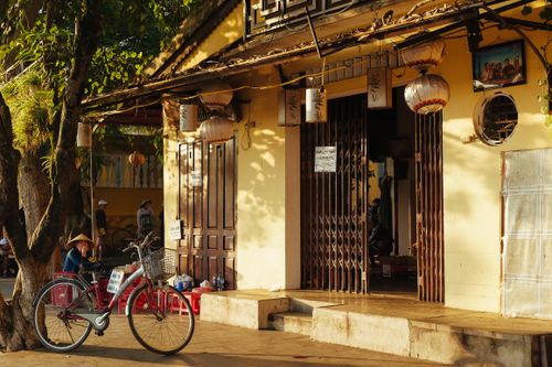 Free Warm street scene featuring a parked bicycle against a traditional yellow building adorned with lanterns. Stock Photo