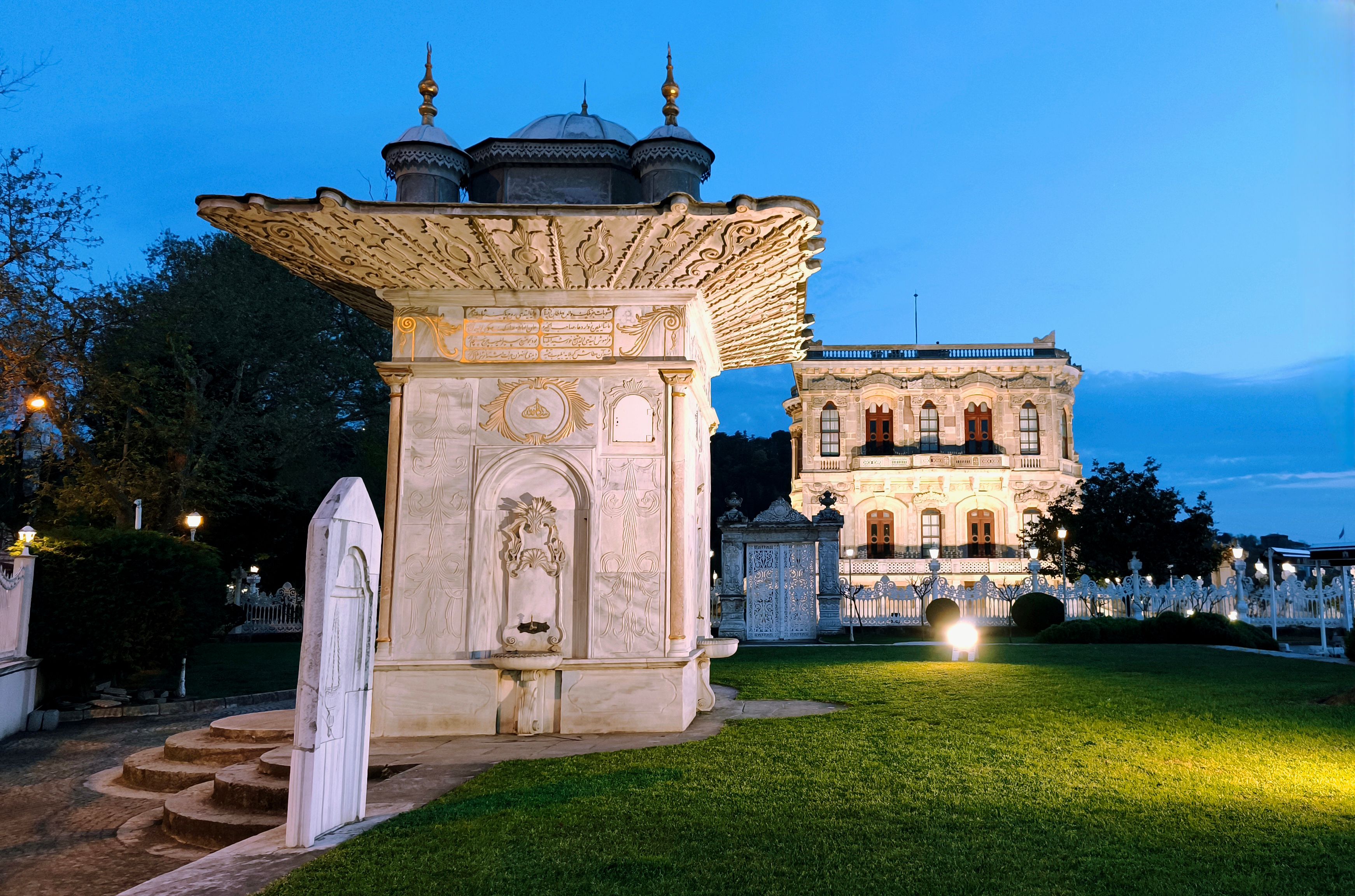 Scenic view of an Ottoman kiosk and palace at sunset in Istanbul's gardens.