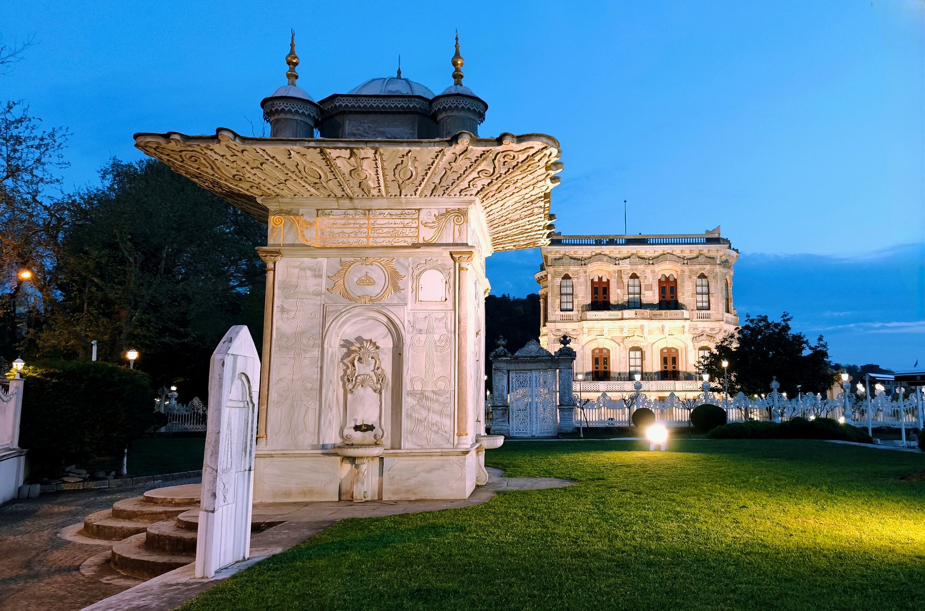 Scenic view of an Ottoman kiosk and palace at sunset in Istanbul's gardens.